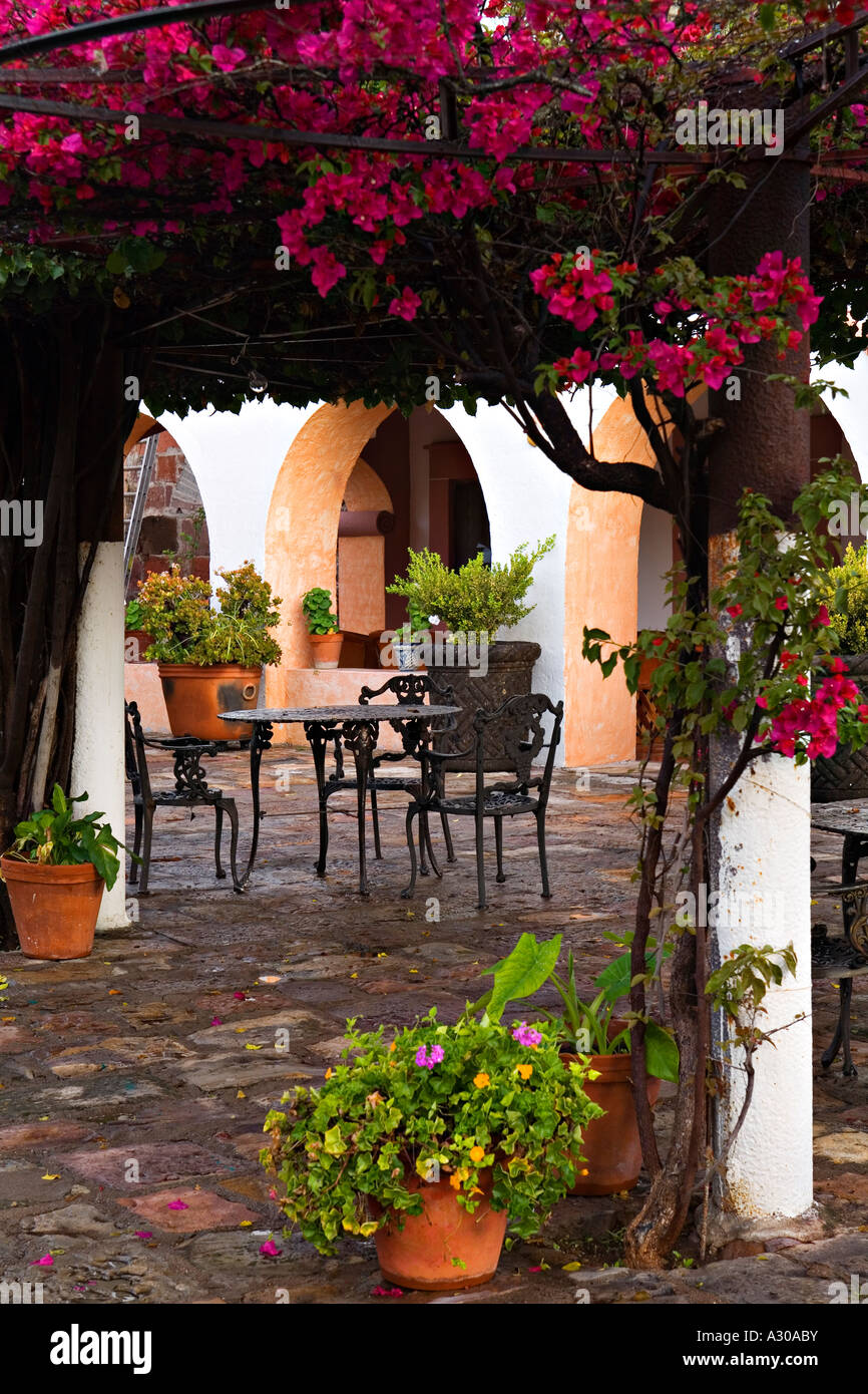 Mexique San Miguel de Allende Bougainvilla croître trellis fer à repasser table et chaises dans la cour de l'hôtel les pots de fleurs Banque D'Images