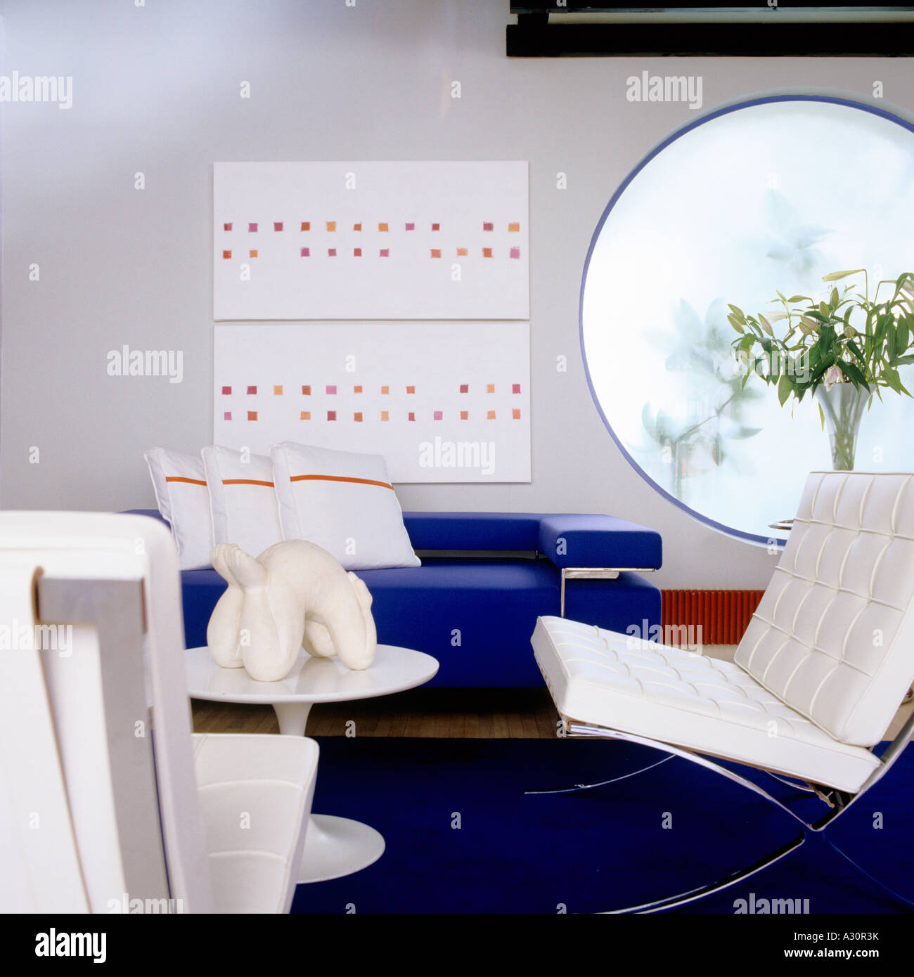 Chaise Barcelone moderne blanc sur la moquette bleue dans la chambre avec fenêtre circulaire Banque D'Images