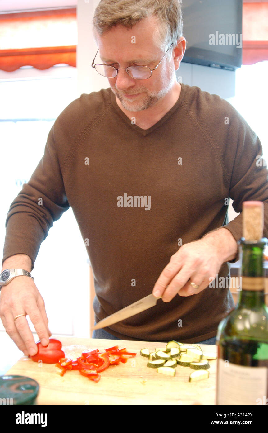 Homme d'âge moyen de préparer un repas sain avec des légumes dans sa cuisine à son domicile à Londres UK Banque D'Images