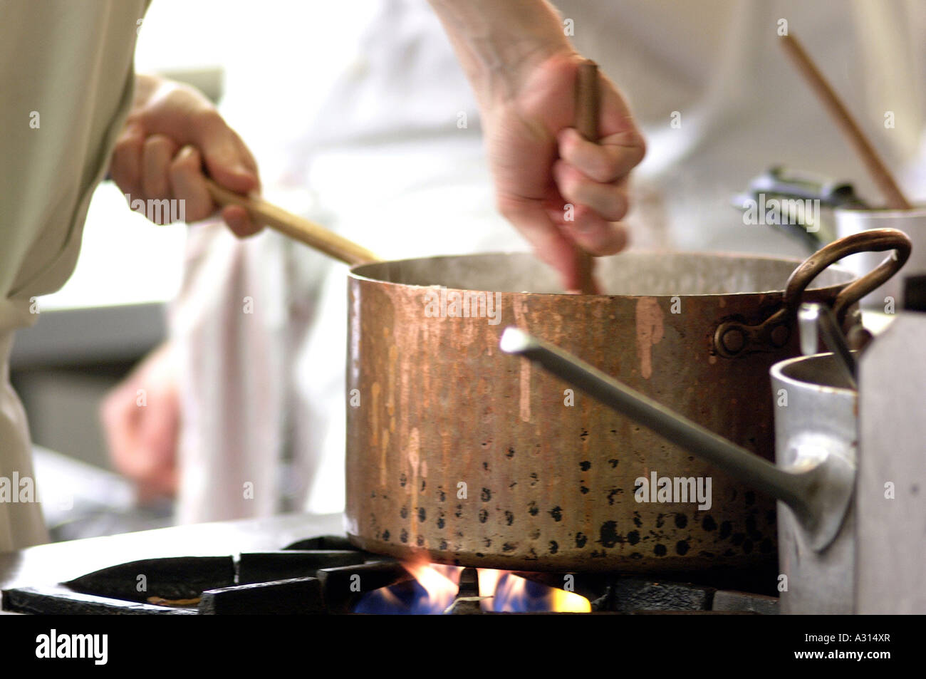 Image libre photo de chef cooking sur cuisinière en remuant une marmite en cuivre dans une cuisine de restaurant commercial britannique London UK Banque D'Images