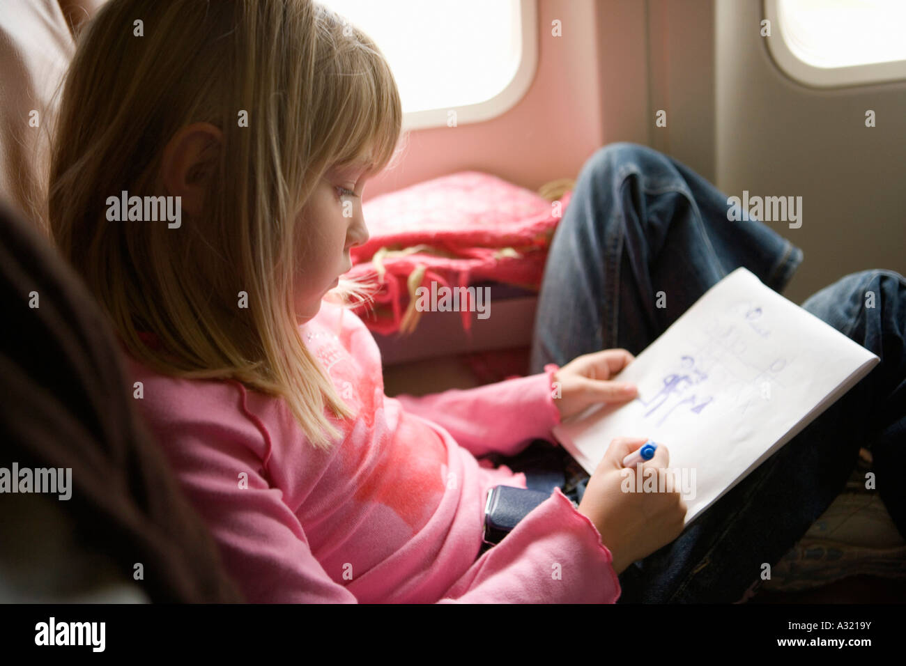 Jeune fille assise dans un avion et de dessin dans un sketch pad Banque D'Images