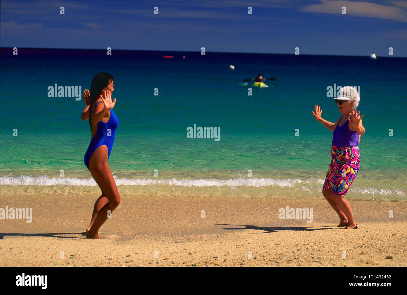 Enseignement femme asiatique de tai chi à senior woman on the beach Banque D'Images