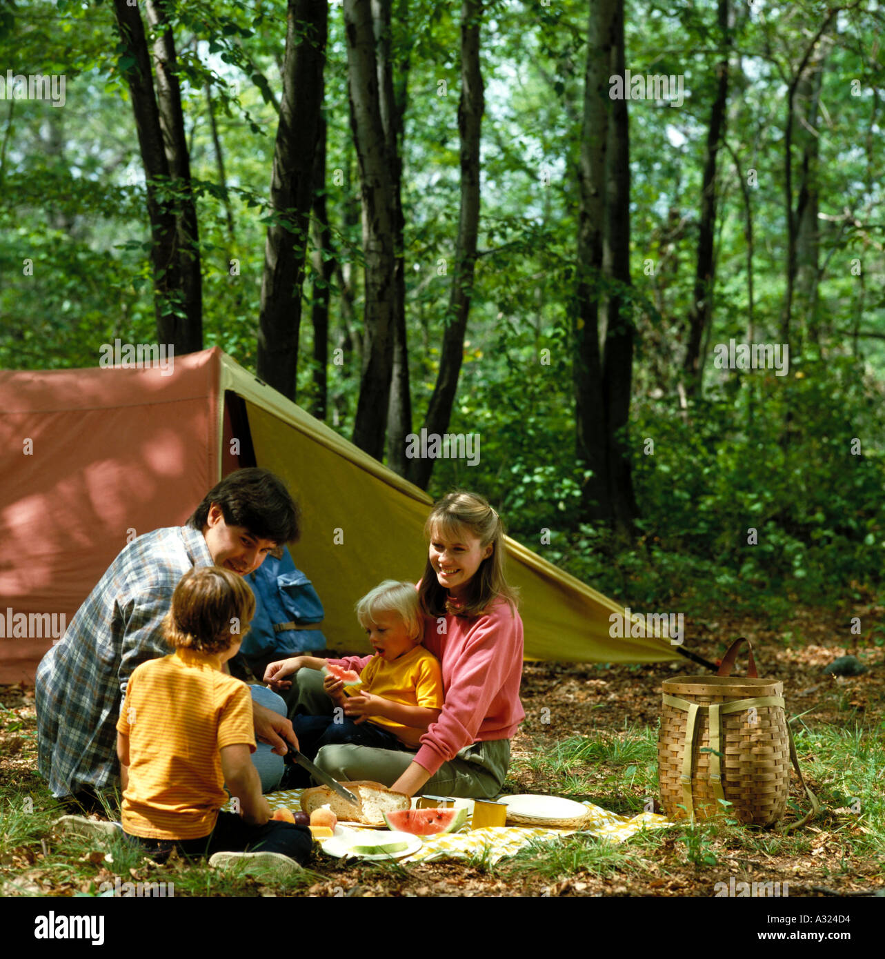 Père et mère de deux enfants ayant un pique-nique dans leur camping en dehors de leur tente Banque D'Images