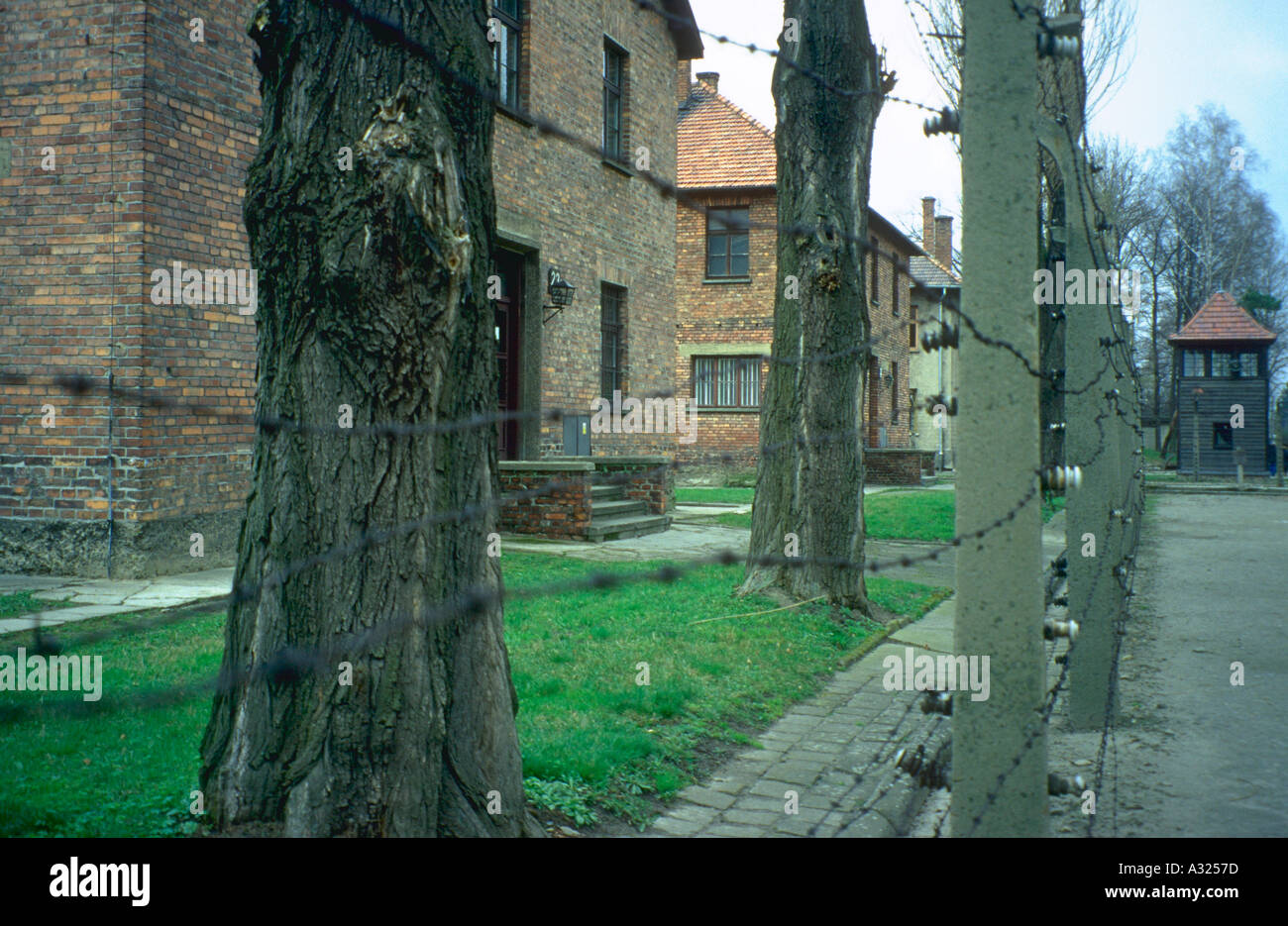 Voir à travers un fil barbelé à l'extérieur des casernes au camp de concentration d'Auschwitz Oswiecim en Pologne Banque D'Images