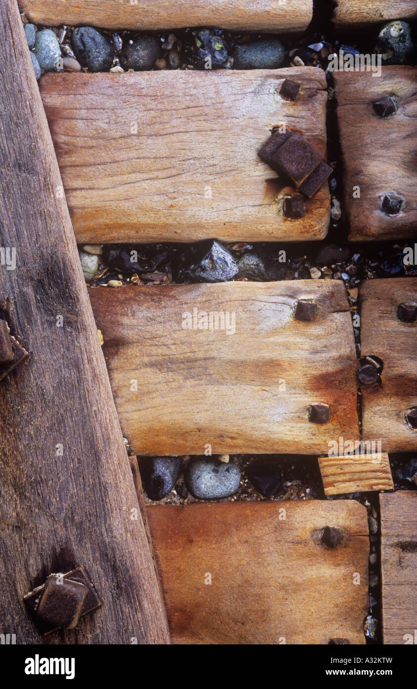 Détail de l'épi de défense contre la mer de bois vissé pour former un mur en bois avec des cailloux dans la mer par la force des fissures Banque D'Images