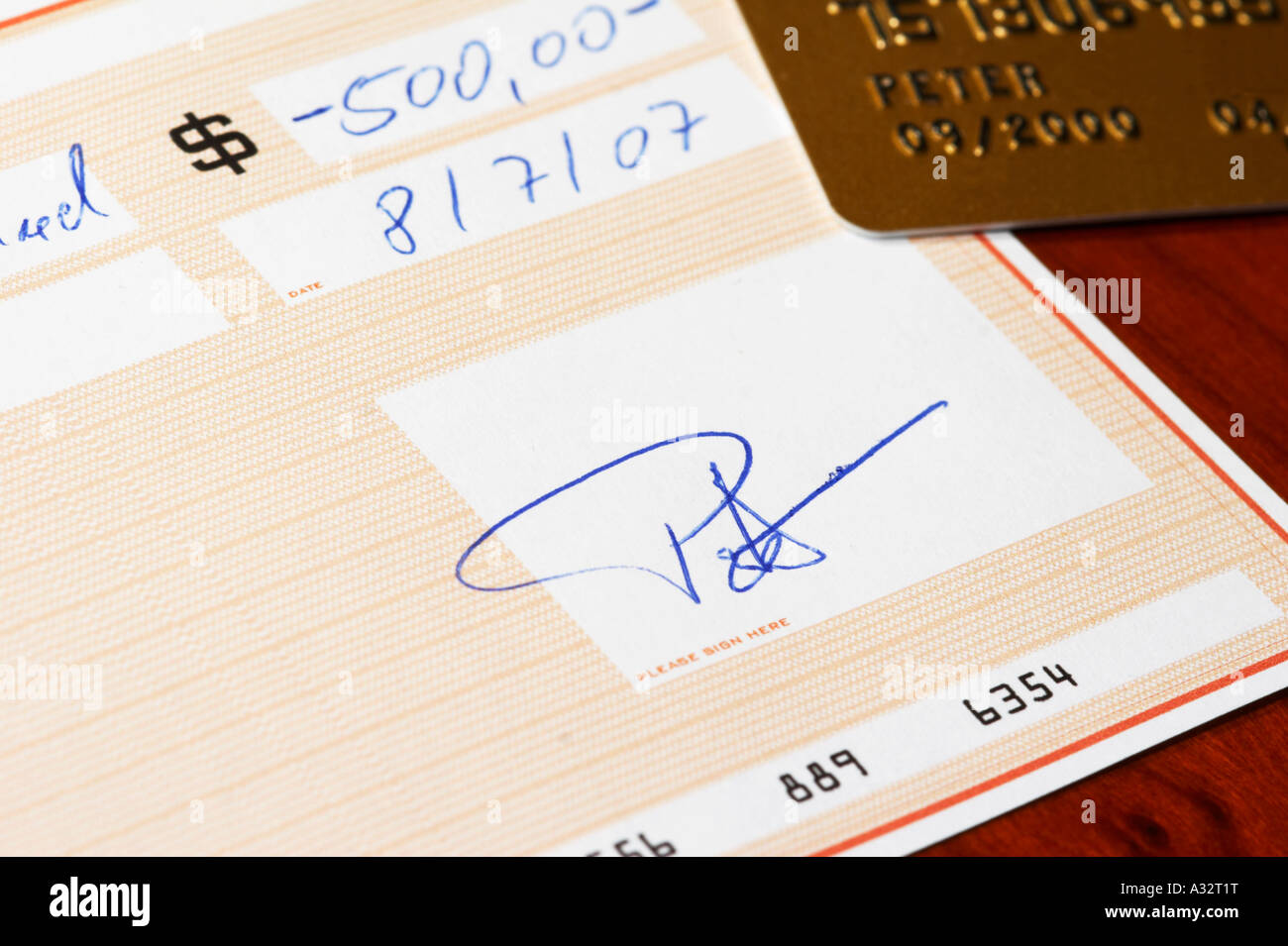 La signature d'un chèque bancaire sur un bureau Banque D'Images