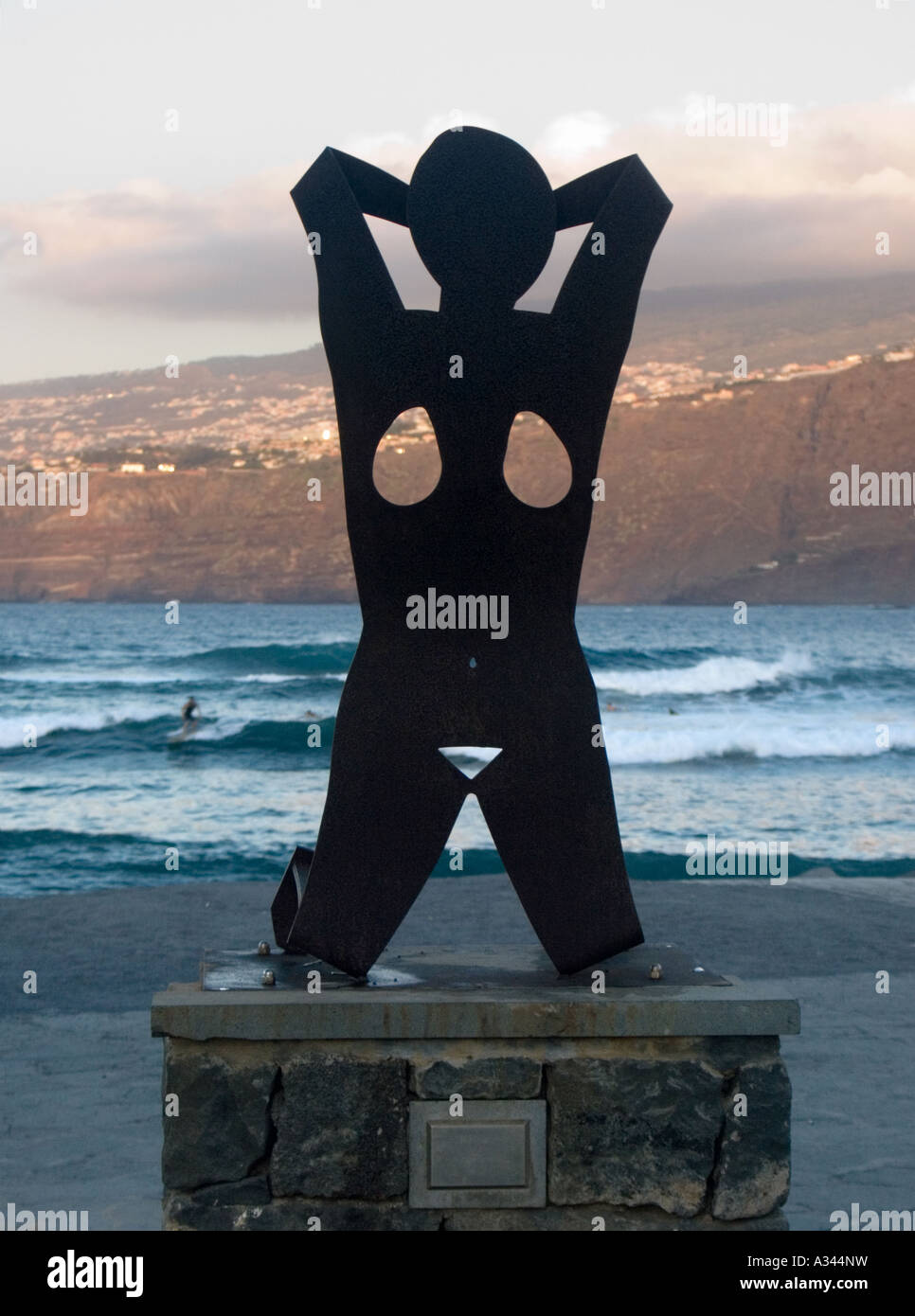 Sculpture d'une femme nue contre les falaises d'or rose et de surf et les nuages reflétant le soleil du soir, Puerto de la Cruz, Tenerife Banque D'Images