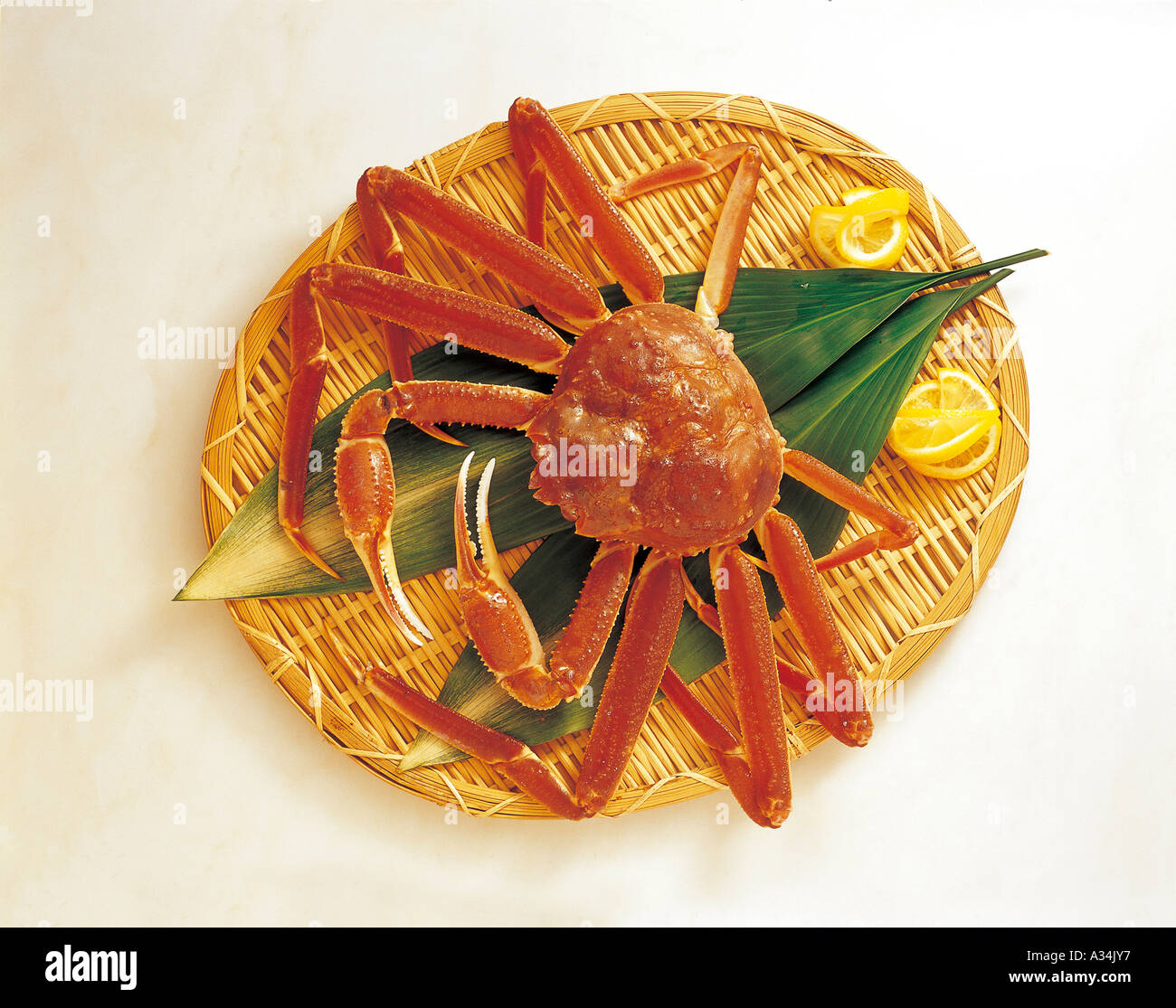 Un crabe servi dans un panier en bois, décoré avec des feuilles vertes et citron Banque D'Images