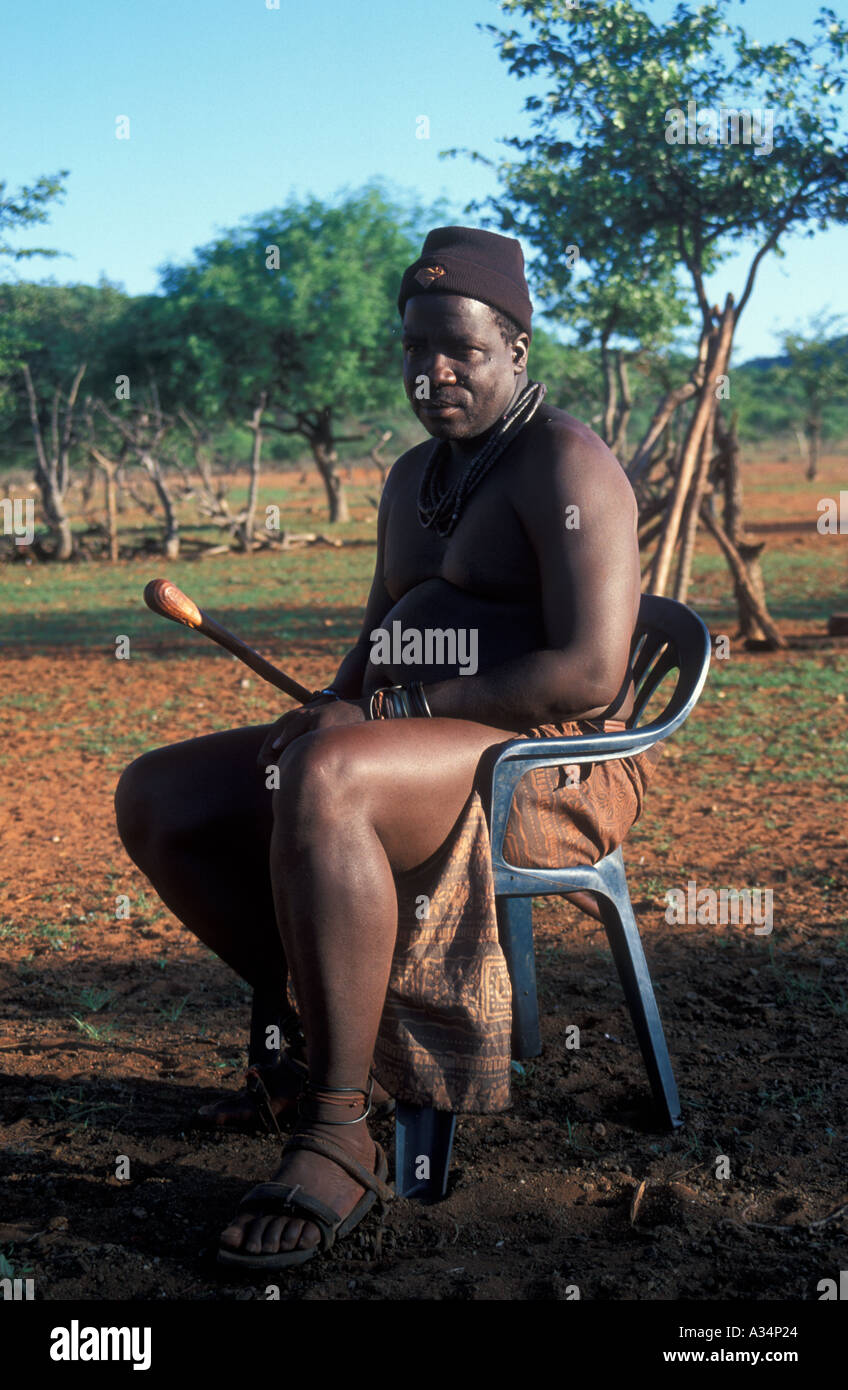 Tribu Himba Ovahimba homme assis dans la chaise en plastique à l'intérieur pour accueillir les visiteurs Kraal Koakoveld Afrique Namibie Banque D'Images