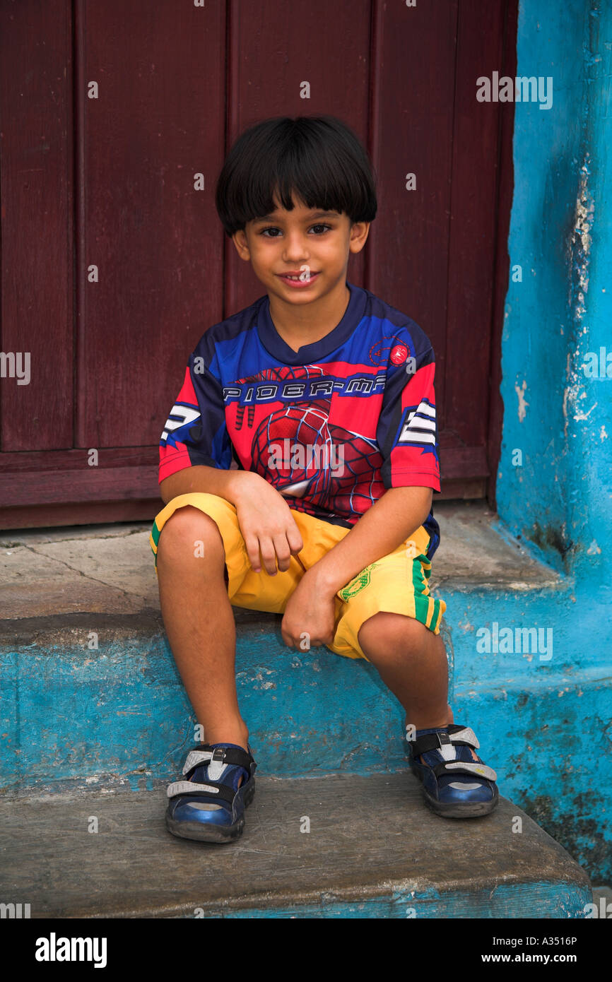 Jeune garçon assis sur une porte en face de son domicile, Camaguey, Cuba, Camagüey Province Banque D'Images