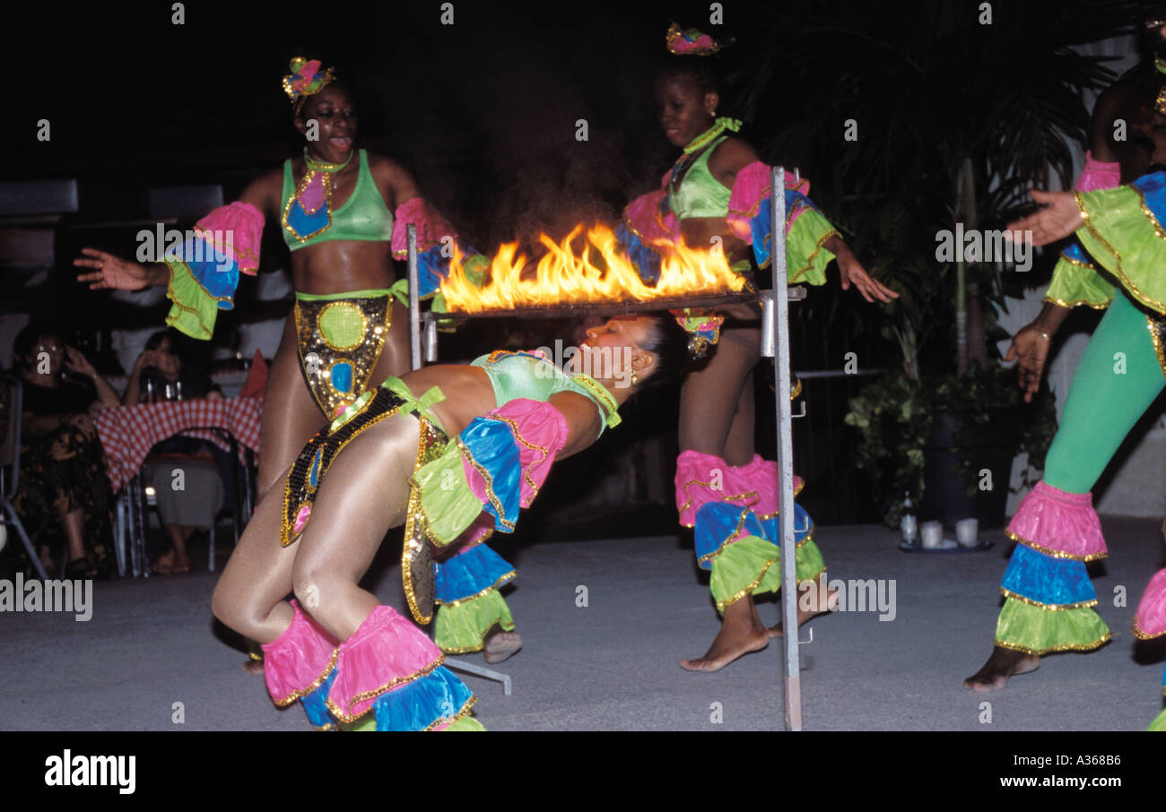 Une femme danseuse limbo bend en arrière pour passer sous une barre enflammée lors d'une performance à un resort hotel Banque D'Images