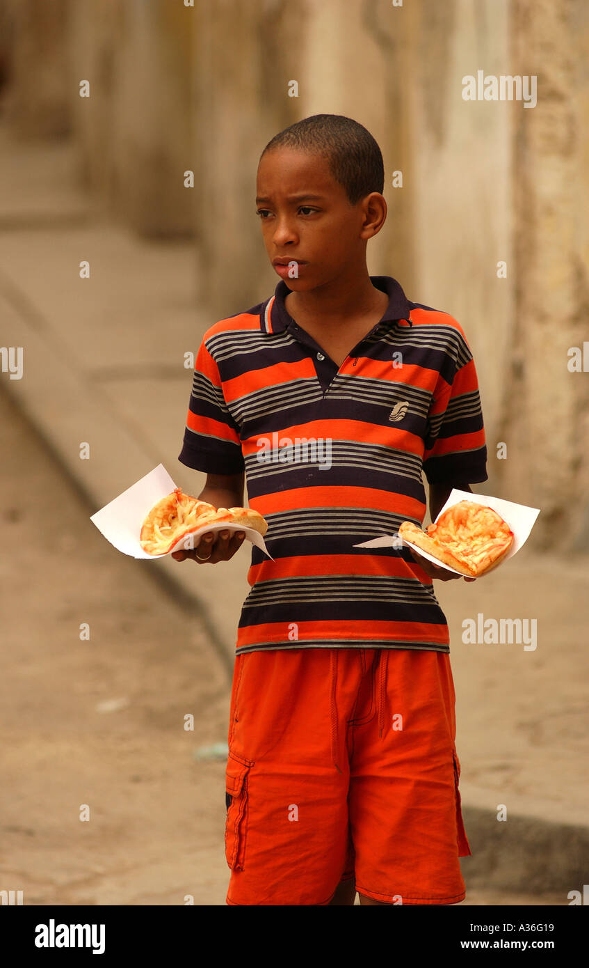 Garçon debout dans la rue qui tiennent de la nourriture La Havane Cuba Banque D'Images