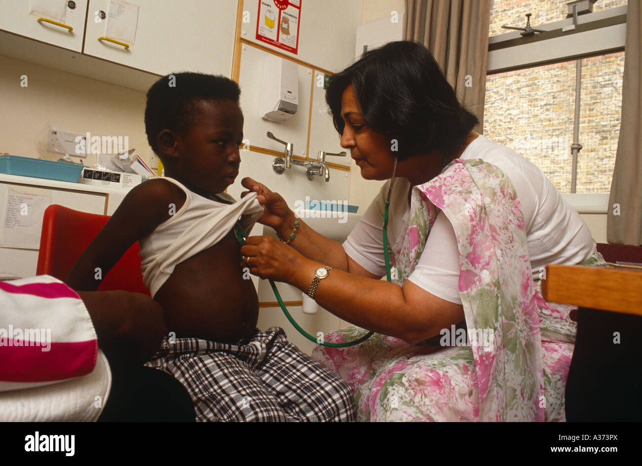 Une femme médecin asiatique examine un enfant dans sa chirurgie à London UK Banque D'Images