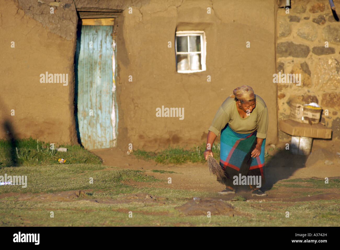 Une femme Basotho nettoie devant son domicile dans le village de montagne Les Lagier au Lesotho. Banque D'Images