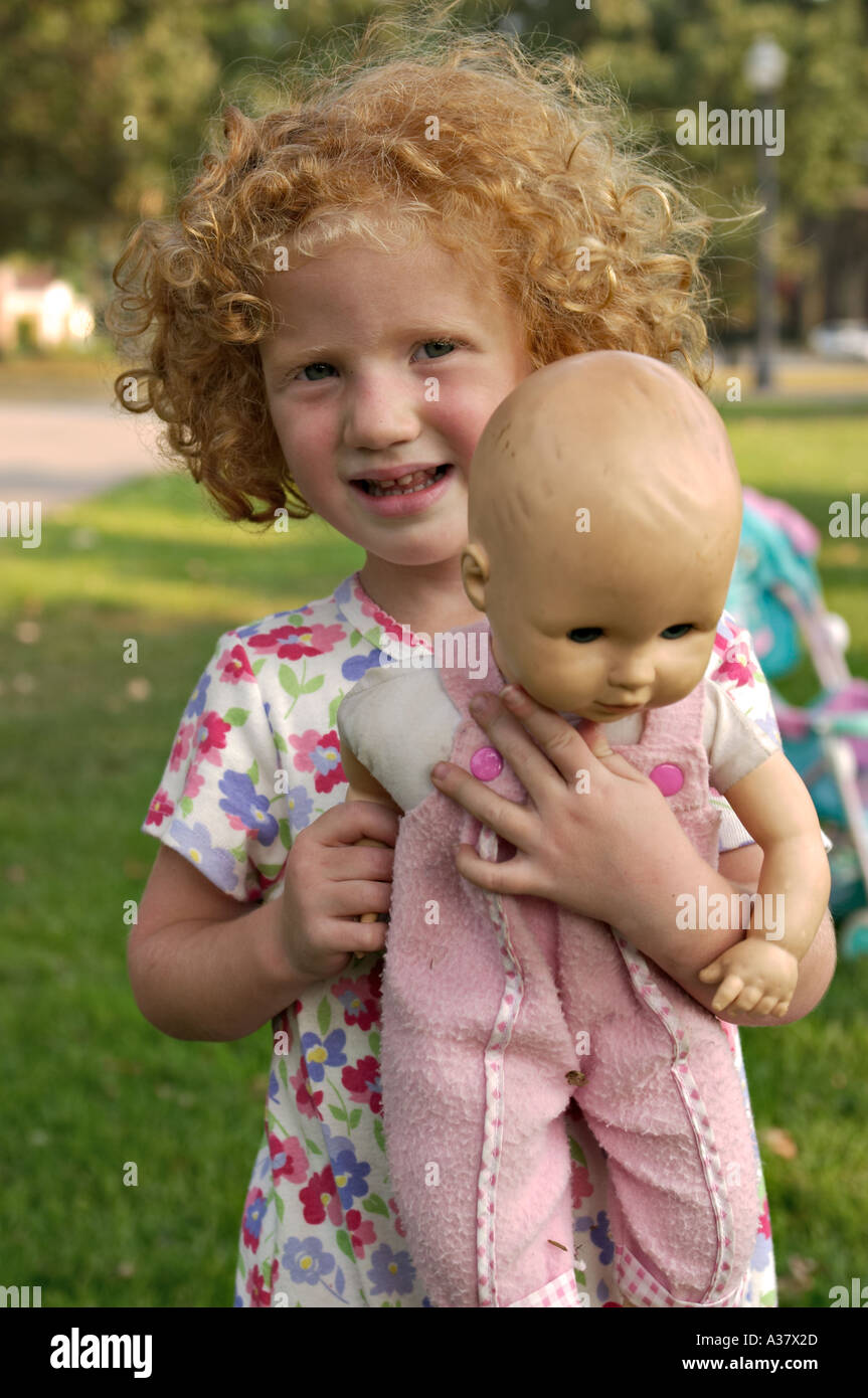 L'ILLINOIS Northbrook jeune fille aux cheveux rouges bouclés tenir doll extérieur dans park Banque D'Images