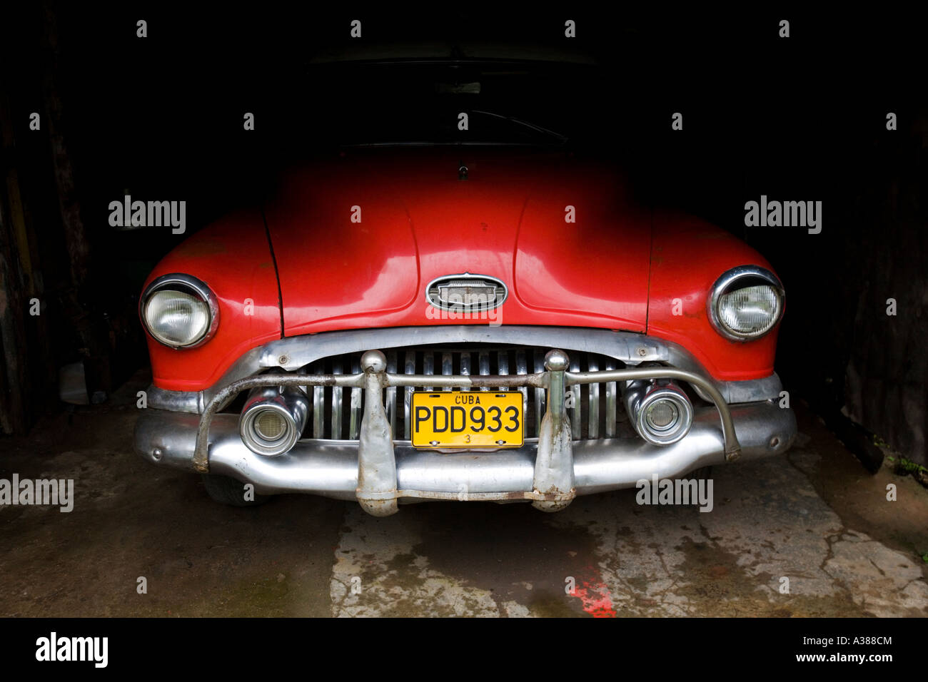 Une voiture américaine classique rouge est assis dans l'ombre d'un garage à Vinales Banque D'Images