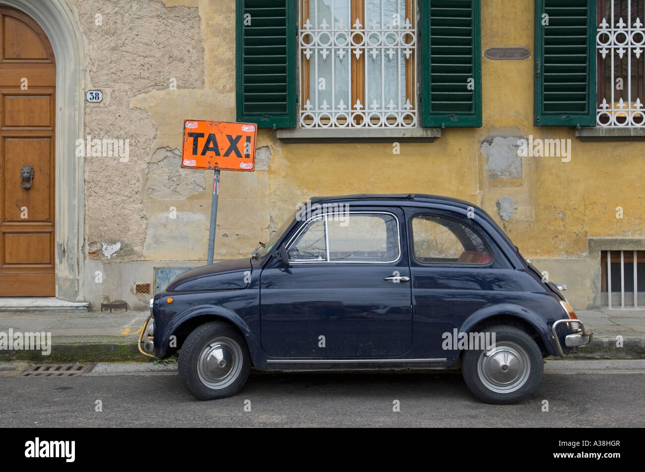 Un vieux classique Fiat 500 bleu foncé garé sur la route ironiquement à côté d'un 'TAXI'. Banque D'Images