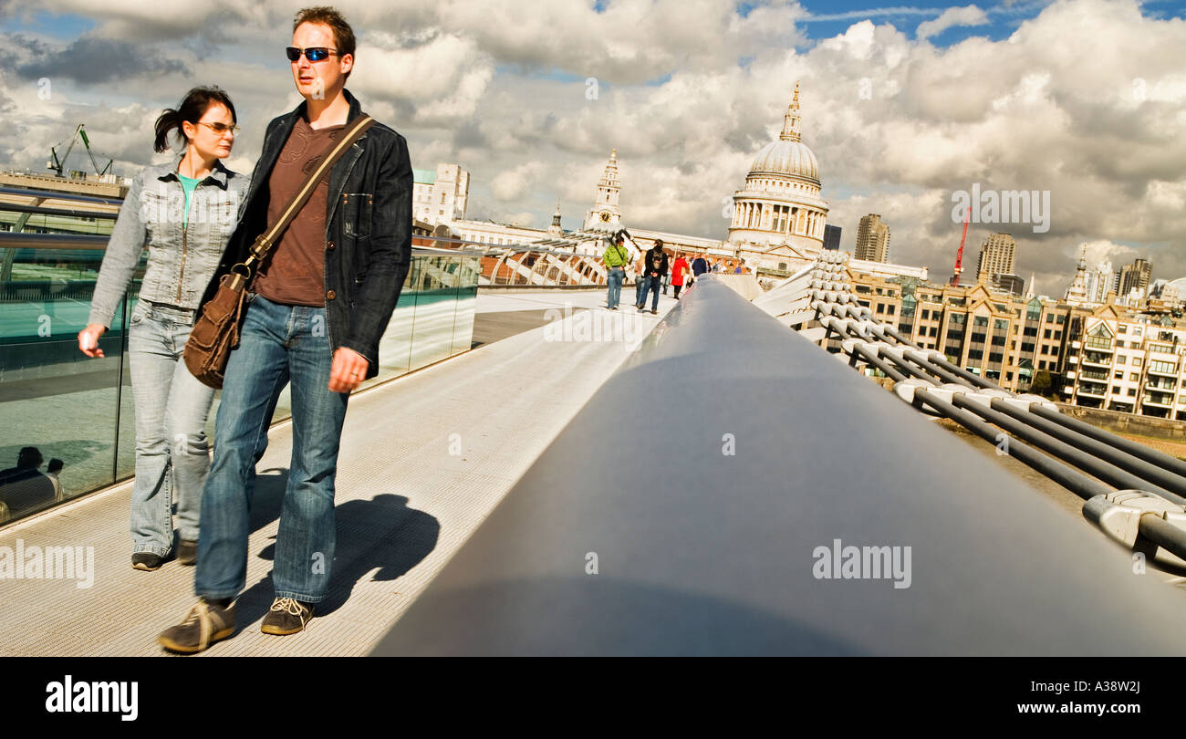 Deux personnes traversent le pont du millénaire de l'autre côté de la rivière Thames, London England UK Banque D'Images