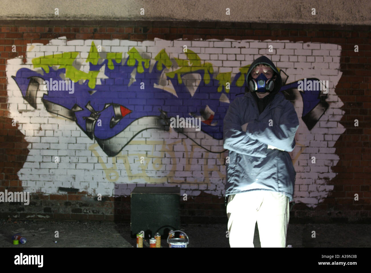 Artiste graffiti tag debout devant des caméra tag portant haut à capuchon de protection et masque de visage Belfast Banque D'Images