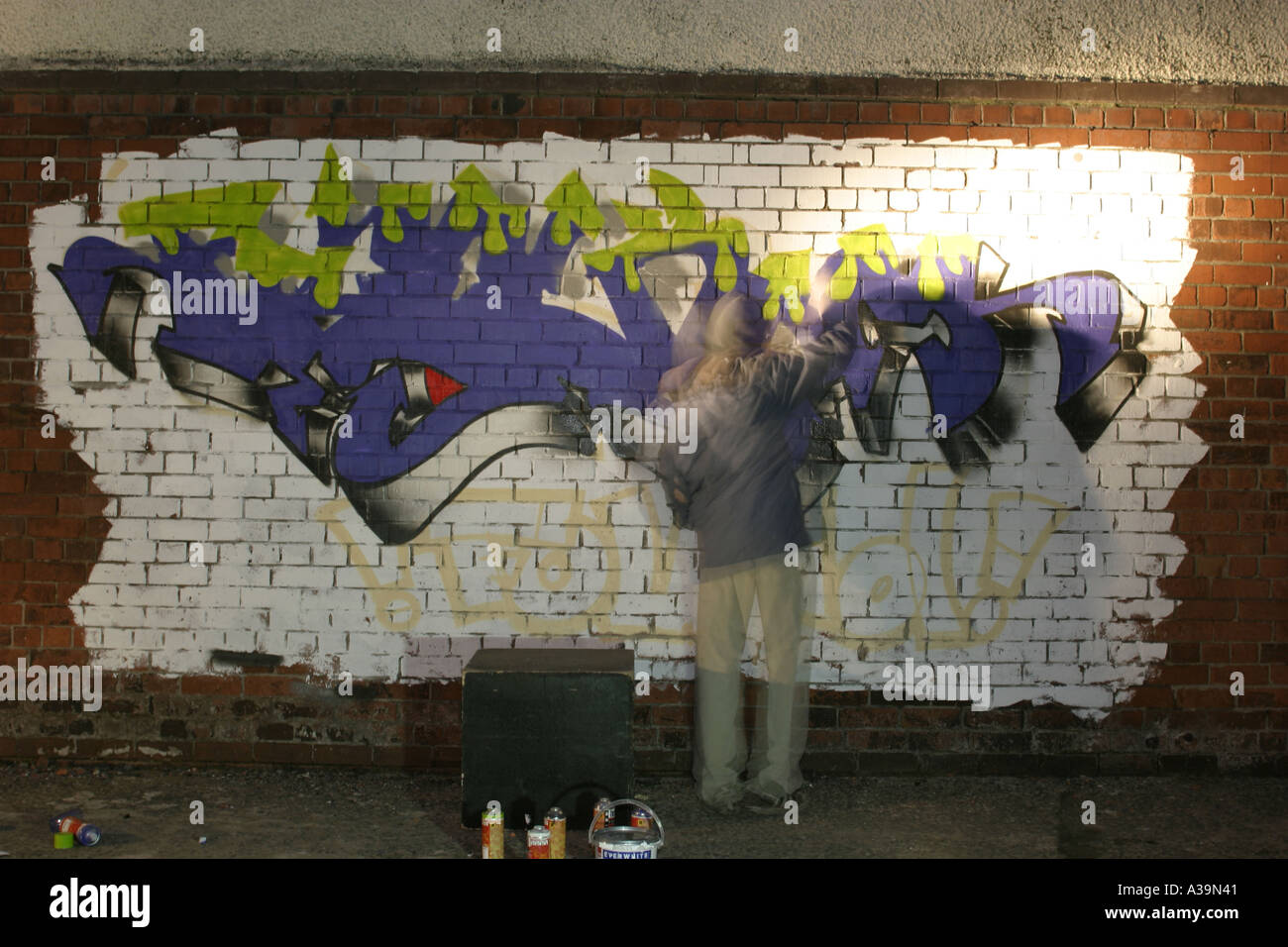 Graffiti Tag artiste au travail avec la peinture en aérosol peut porter haut à capuchon de protection et masque de visage de l'Irlande du Nord Belfast Banque D'Images
