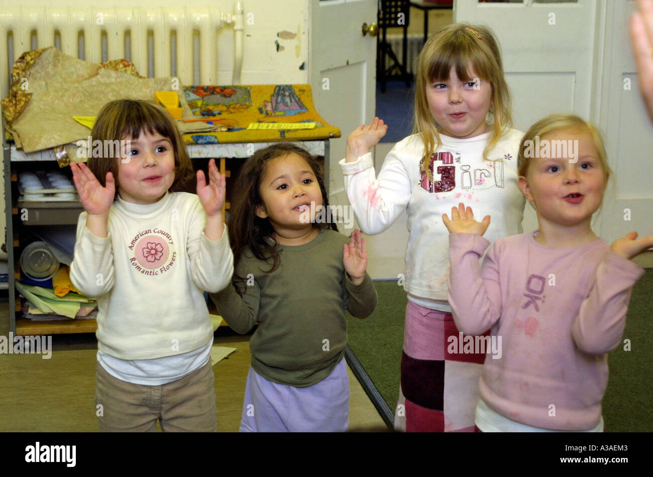 Nursery School girls applaudissant et chantant en classe. Banque D'Images