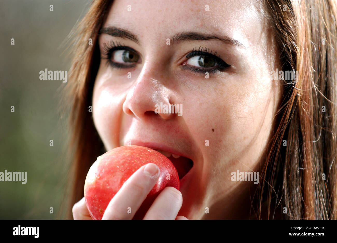 Jeune femme adolescent mordre dans une pomme Pink Lady Banque D'Images