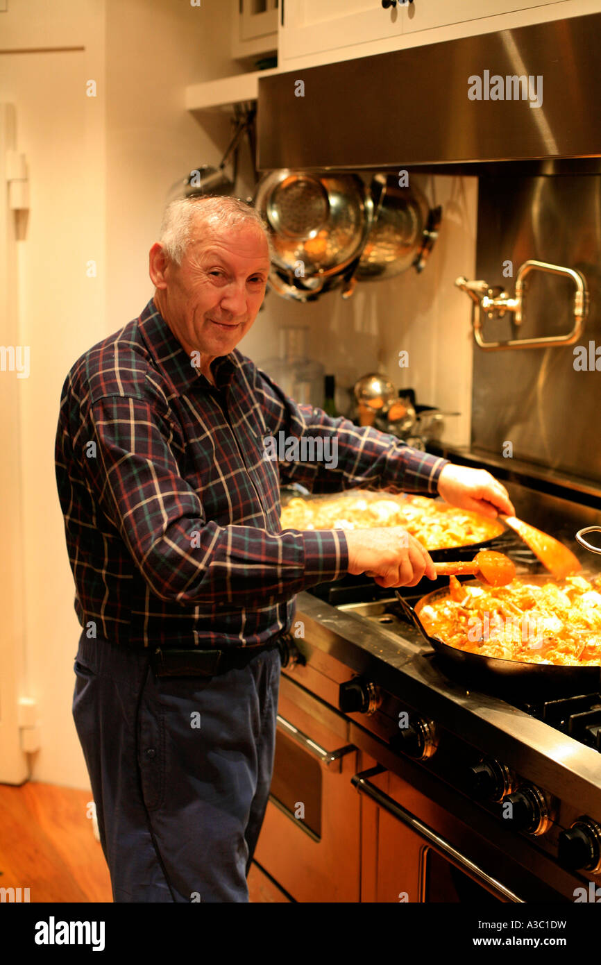 Un homme âgé cuisiniers une paella Banque D'Images