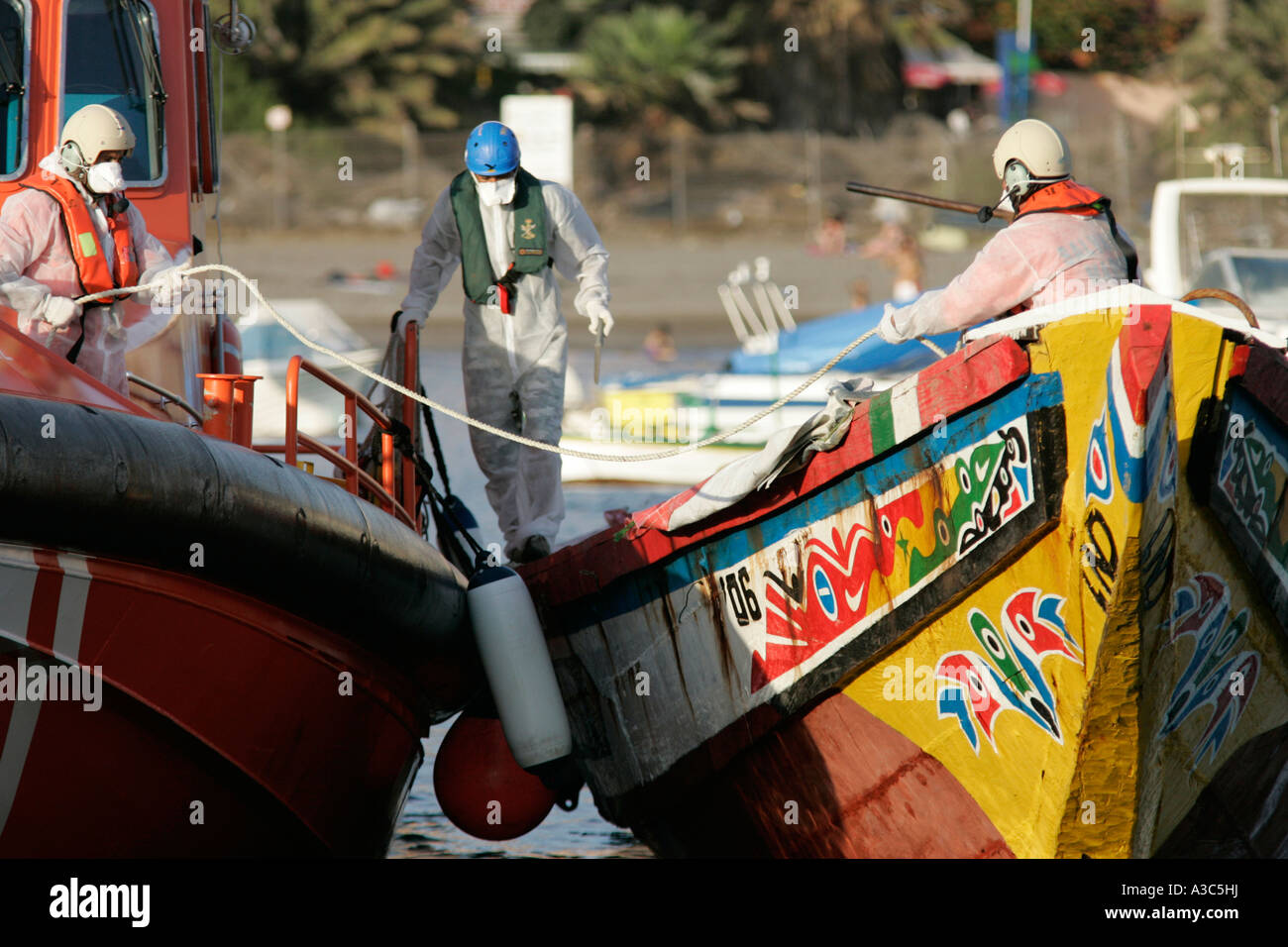 la police espagnole et les fonctionnaires en vêtements de protection et masques orange maritimo salvamento recherche de bateaux de pêche migrants africains illégaux scène Banque D'Images