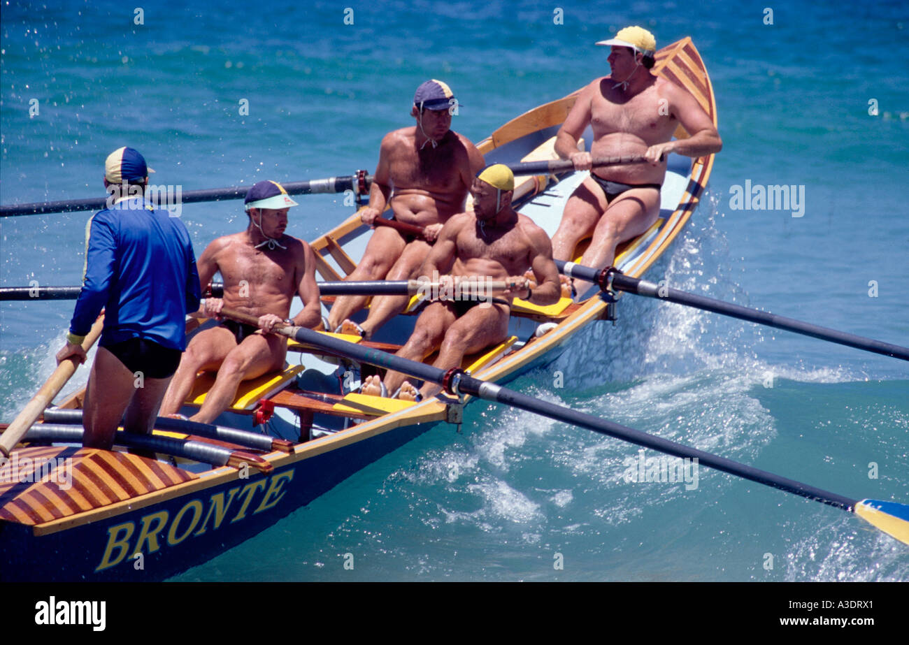 Bateau de sauvetage sur plage avec cinq hommes à bord de partir sur une vague à Bondi Beach, Sydney, Australie Banque D'Images