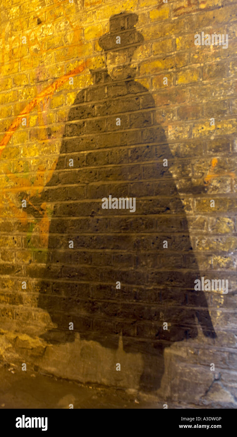 Le Graffiti d'un homme portant une cape et tenant un peut de sprayon un mur dans Brick Lane, London Banque D'Images