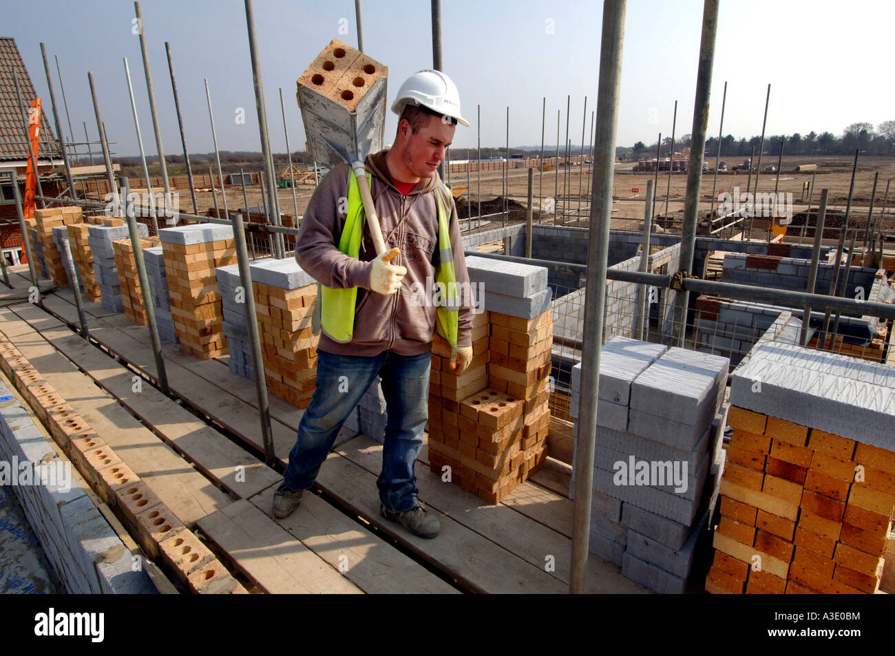 Un jeune travailleur transporteur hod sur un chantier avec une charge de briques Banque D'Images