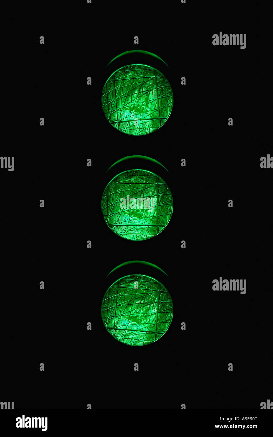 Feu de signalisation avec trois voyants verts allumés la nuit en donnant le feu vert Banque D'Images