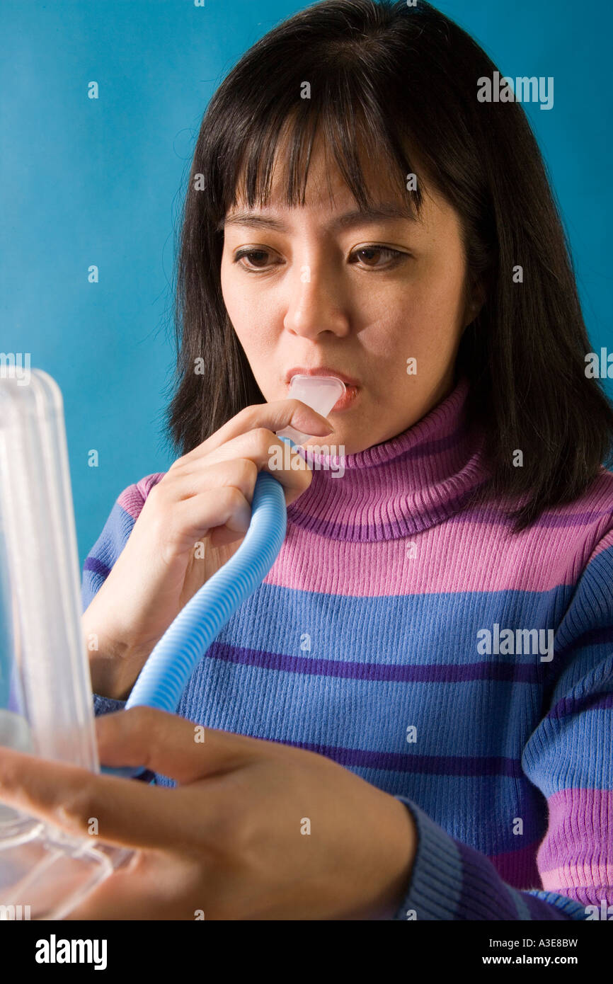 Femme Asiatique souffle dans un tube respiratoire pour flotter les billes à l'intérieur des tubes en plastique pour mesurer l'affection pulmonaire. Banque D'Images