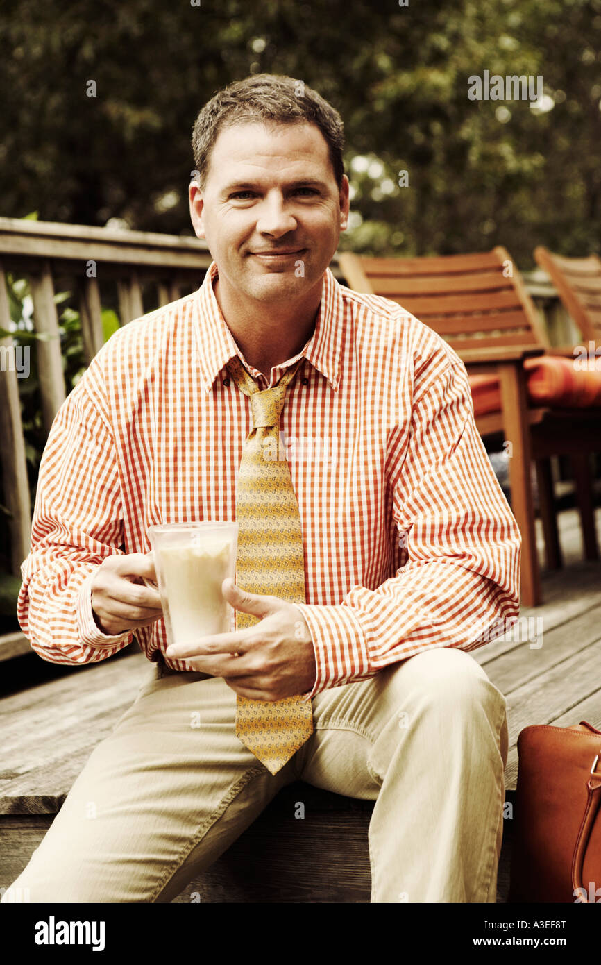 Portrait of a businessman holding a mug de milkshake et smiling Banque D'Images