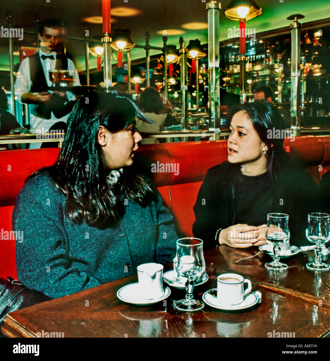 Deux filles françaises féminines asiatiques adolescents discutant dans le café français Paris, France, boire un café, adolescents traînant un café, femme française paris café, Banque D'Images