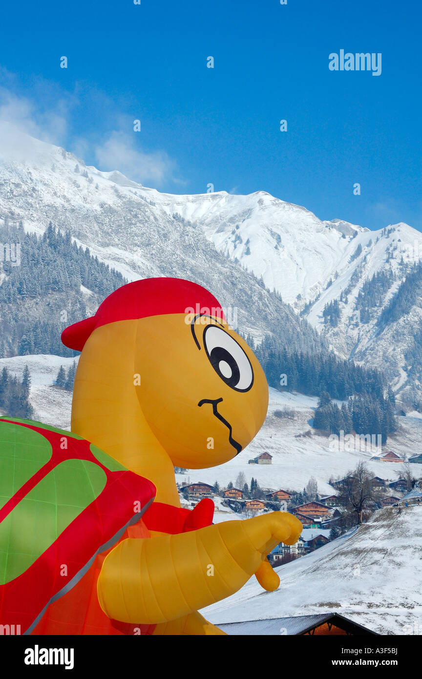 Un ballon gonflé d'être comique au château d'Oex de montgolfières, qui pèse sur le village, les Alpes enneigées en arrière-plan Banque D'Images