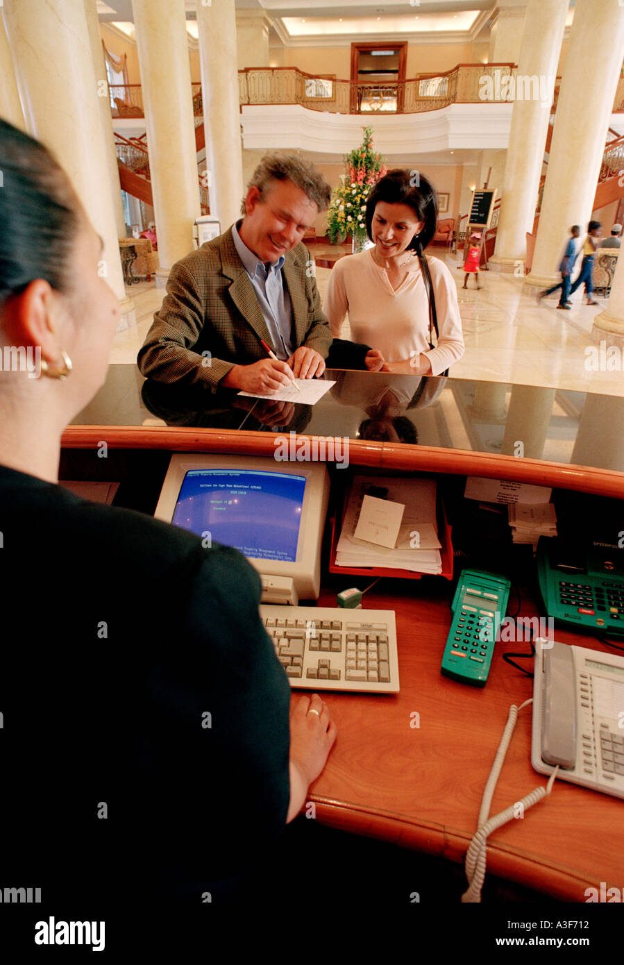 Contrôle de couple à l'hôtel avec réceptionniste en premier plan Banque D'Images