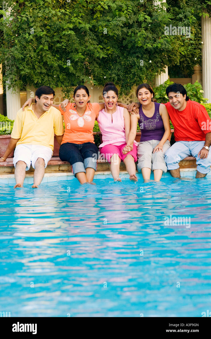 Trois jeunes femmes avec deux jeunes hommes assis au bord de l'eau Banque D'Images