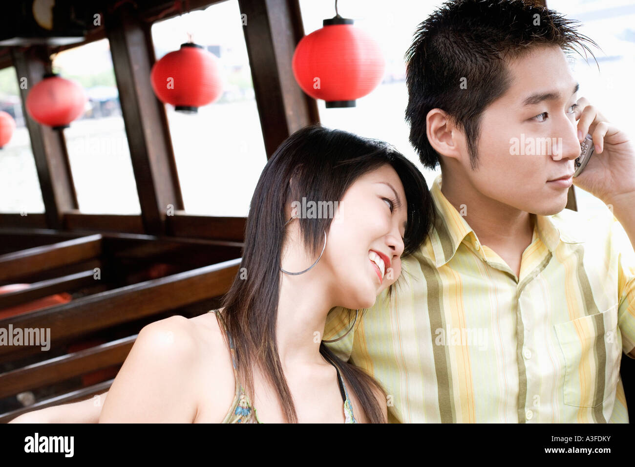 Close-up of a young man talking on mobile phone et une jeune femme posant sa tête sur son épaule Banque D'Images