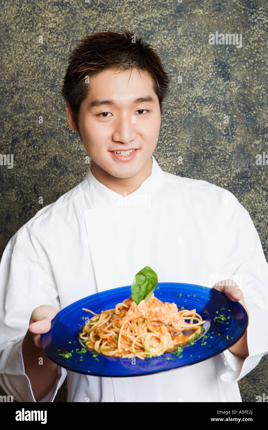 Portrait of a waiter holding a plate of noodles Banque D'Images