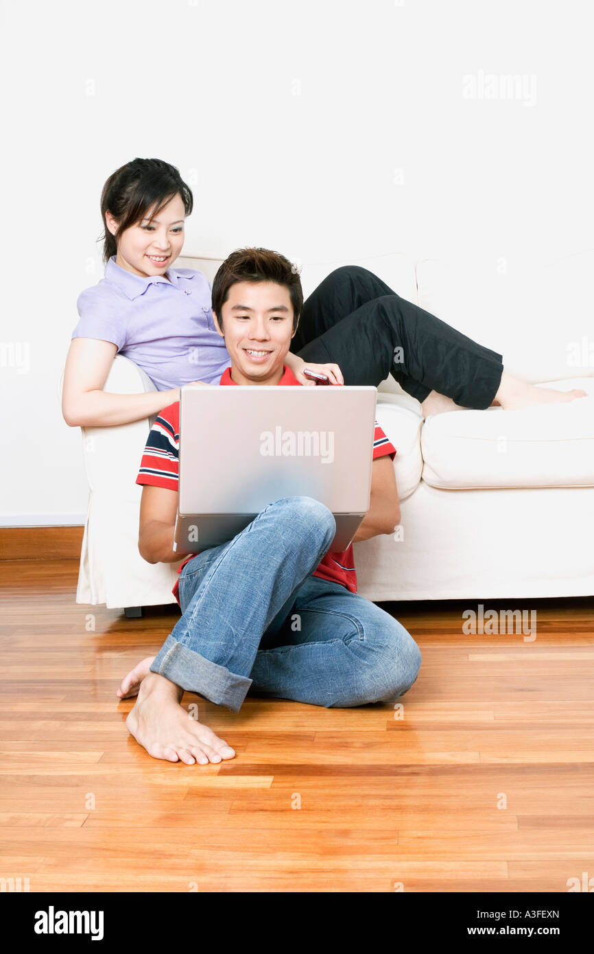 Jeune femme assise sur un canapé avec un mid adult woman using a laptop Banque D'Images
