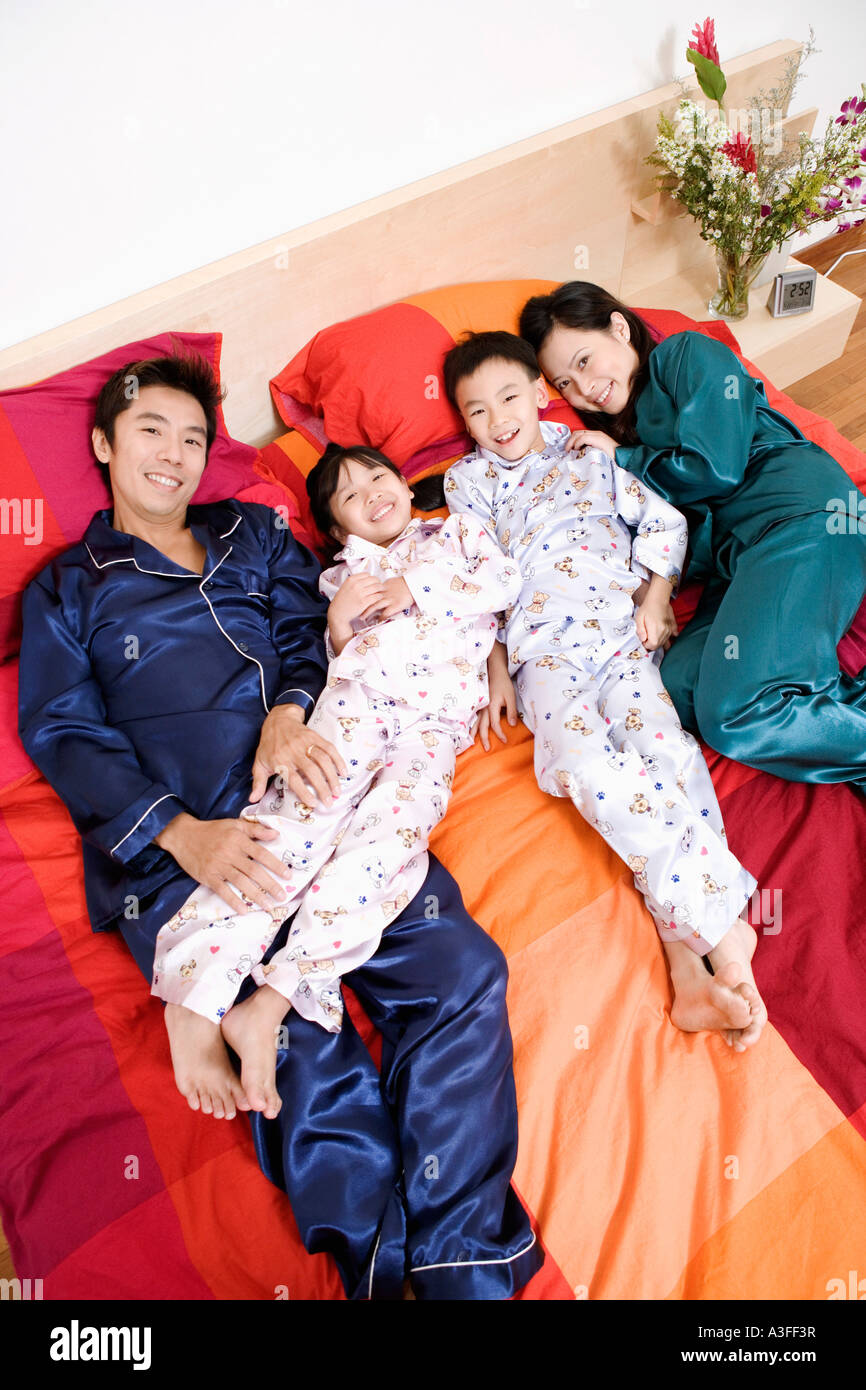 Portrait de deux parents allongé sur le lit avec leurs deux enfants Banque D'Images
