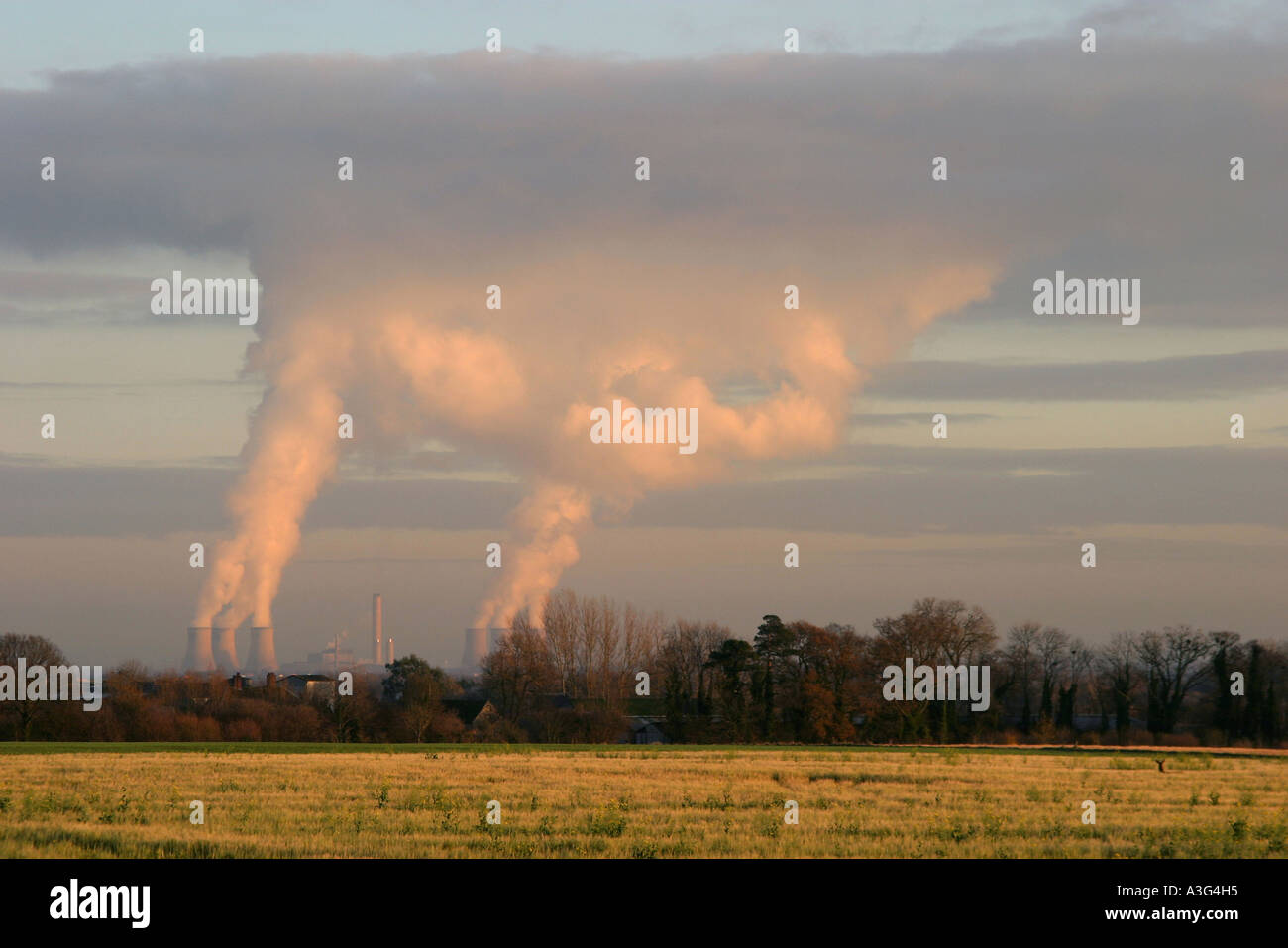 Tours de refroidissement de la vapeur à Didcot power station s'élève à et se mélange avec des nuages bas niveau au coucher du soleil. Banque D'Images