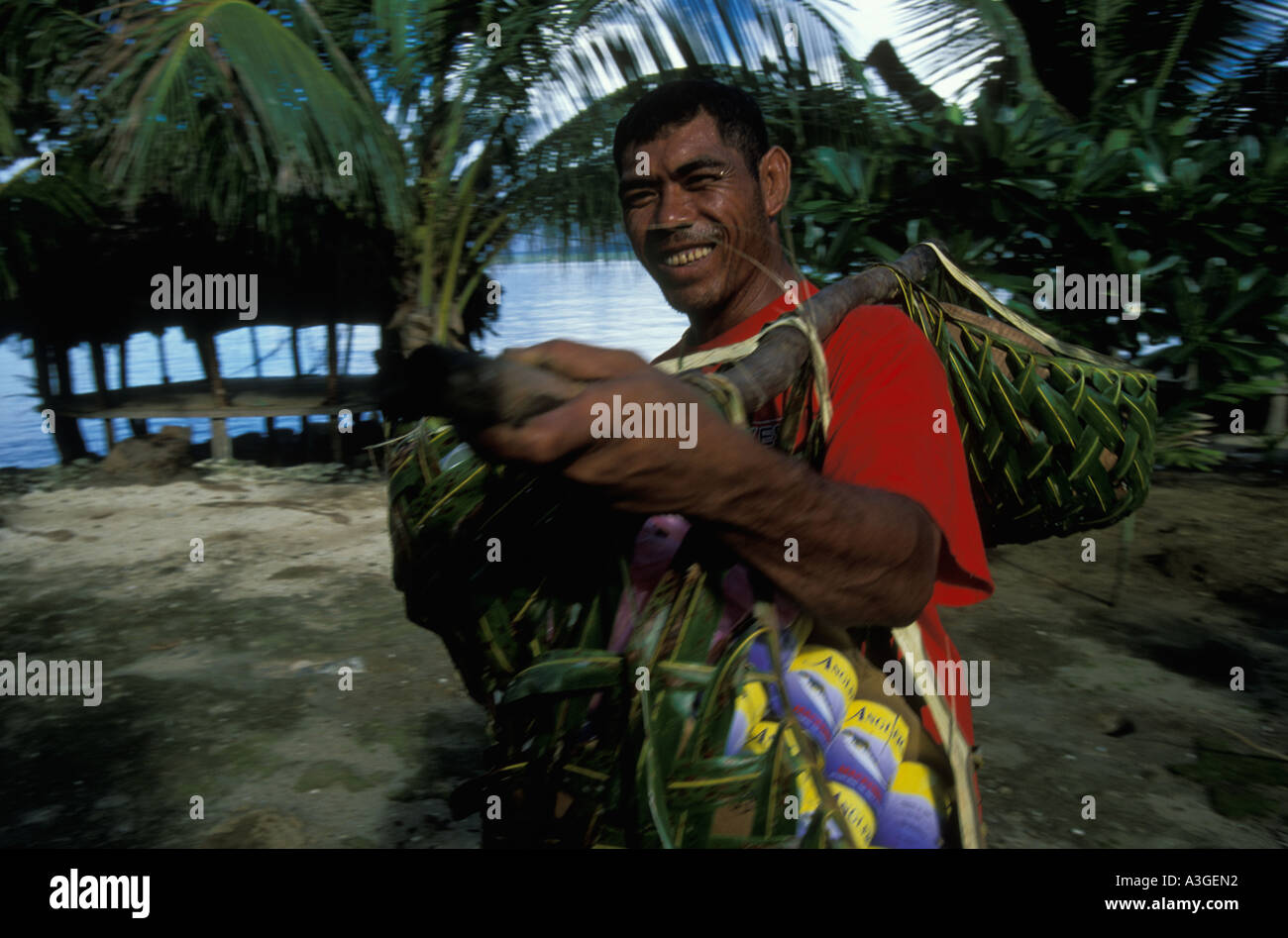 Un homme sur l'île de Manono Samoa porte home produits e g conserve de poisson dans les paniers en feuille de palmier accroché sur un poteau sur son épaule Banque D'Images
