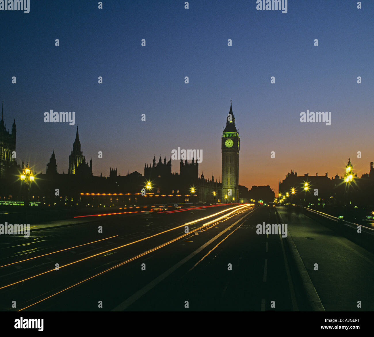 Lumières de la circulation sur le pont de Westminster avec les édifices du Parlement partiellement allumé alors que la nuit tombe Banque D'Images