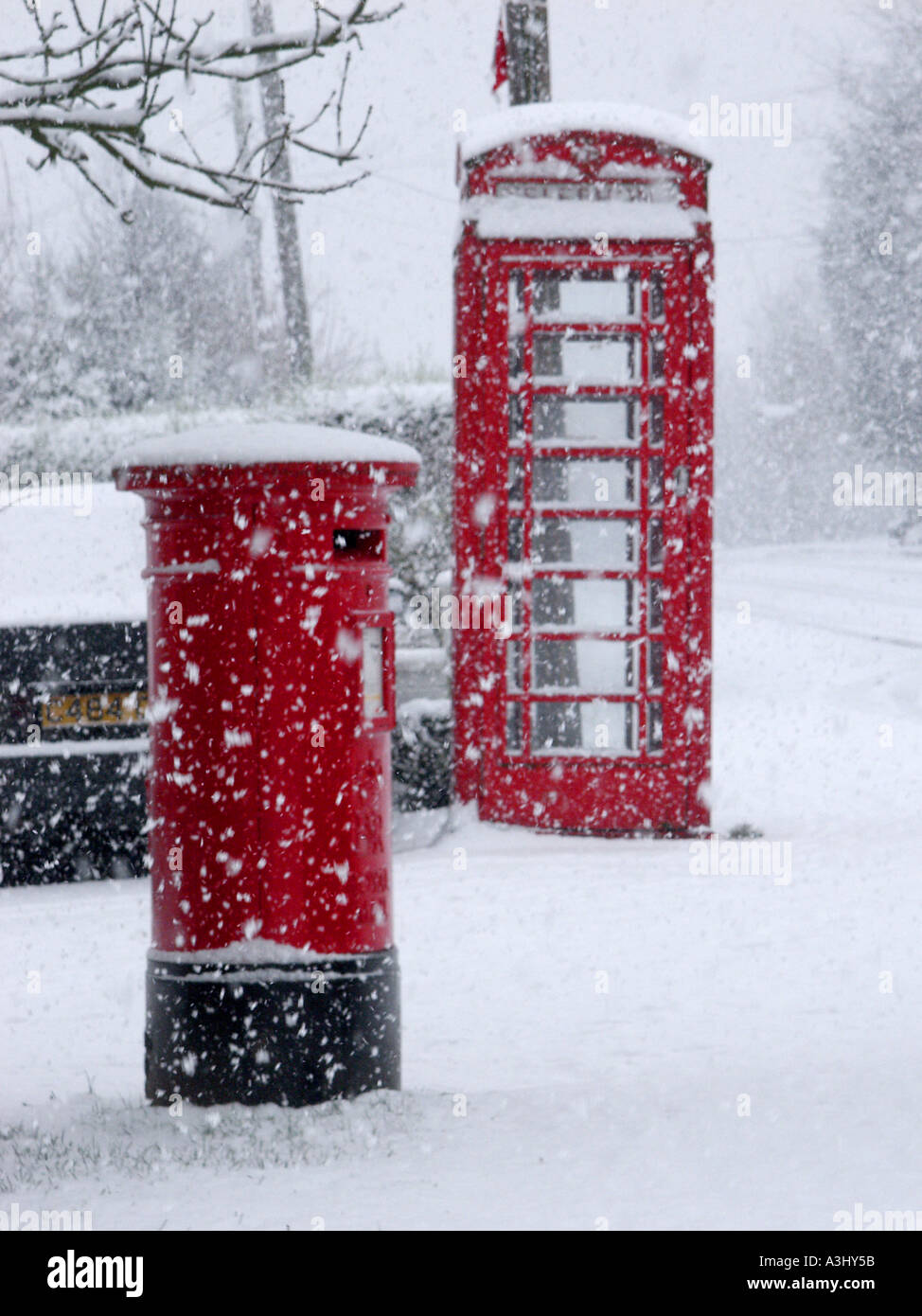 Village rural scène de rue hiver & flocons tomber autour de British Telecom téléphone rouge fort et royal mail pilier lettre fort Essex England UK Banque D'Images
