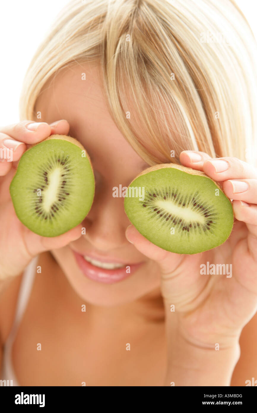 Woman putting kiwis sur ses yeux Banque D'Images