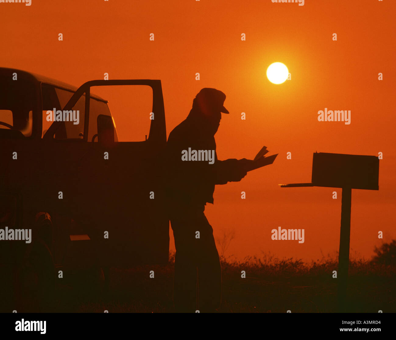 Contrôle de l'homme ferme au coucher du soleil sur la boîte aux lettres Banque D'Images