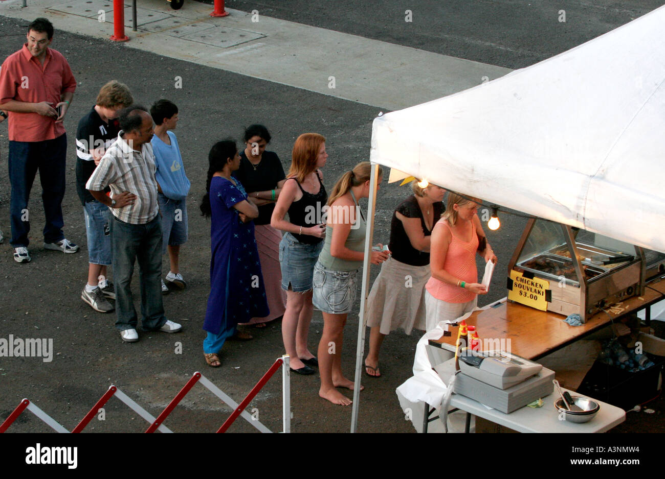 Les gens de beaucoup de races mixtes line up ou d'une file d'attente pour takeawy la nourriture au lieu d'une piscine en plein air Banque D'Images