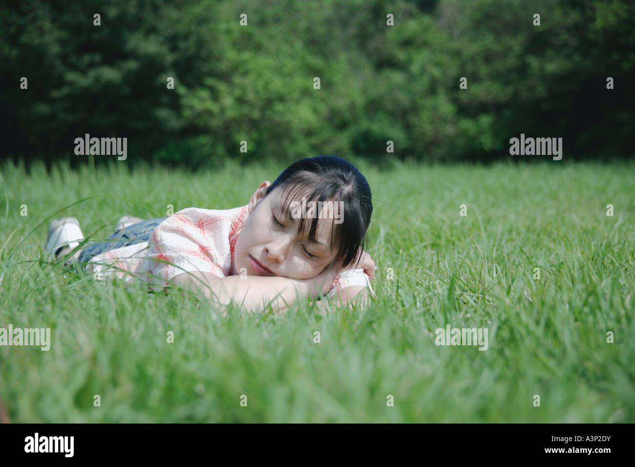 Une jeune femme dormir sur grass field Banque D'Images